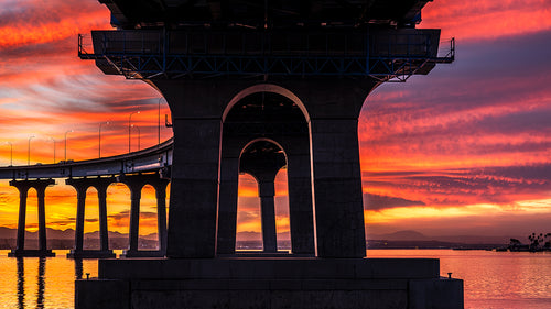 Fiery sunrise beneath the Coronado Bridge at Tidelands Park, reflecting across San Diego Bay